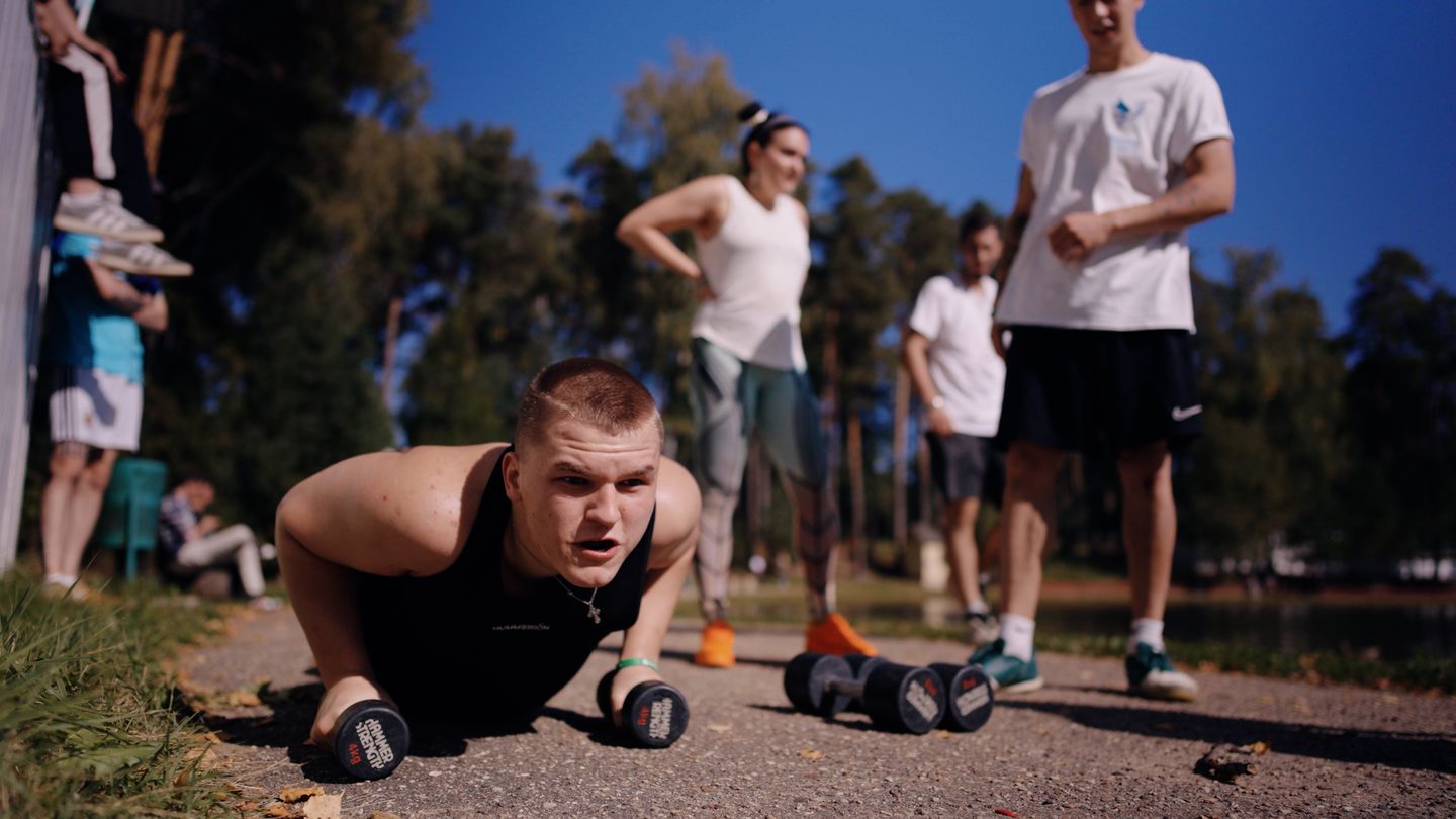 A camp participant does push-ups on dumbbells during training